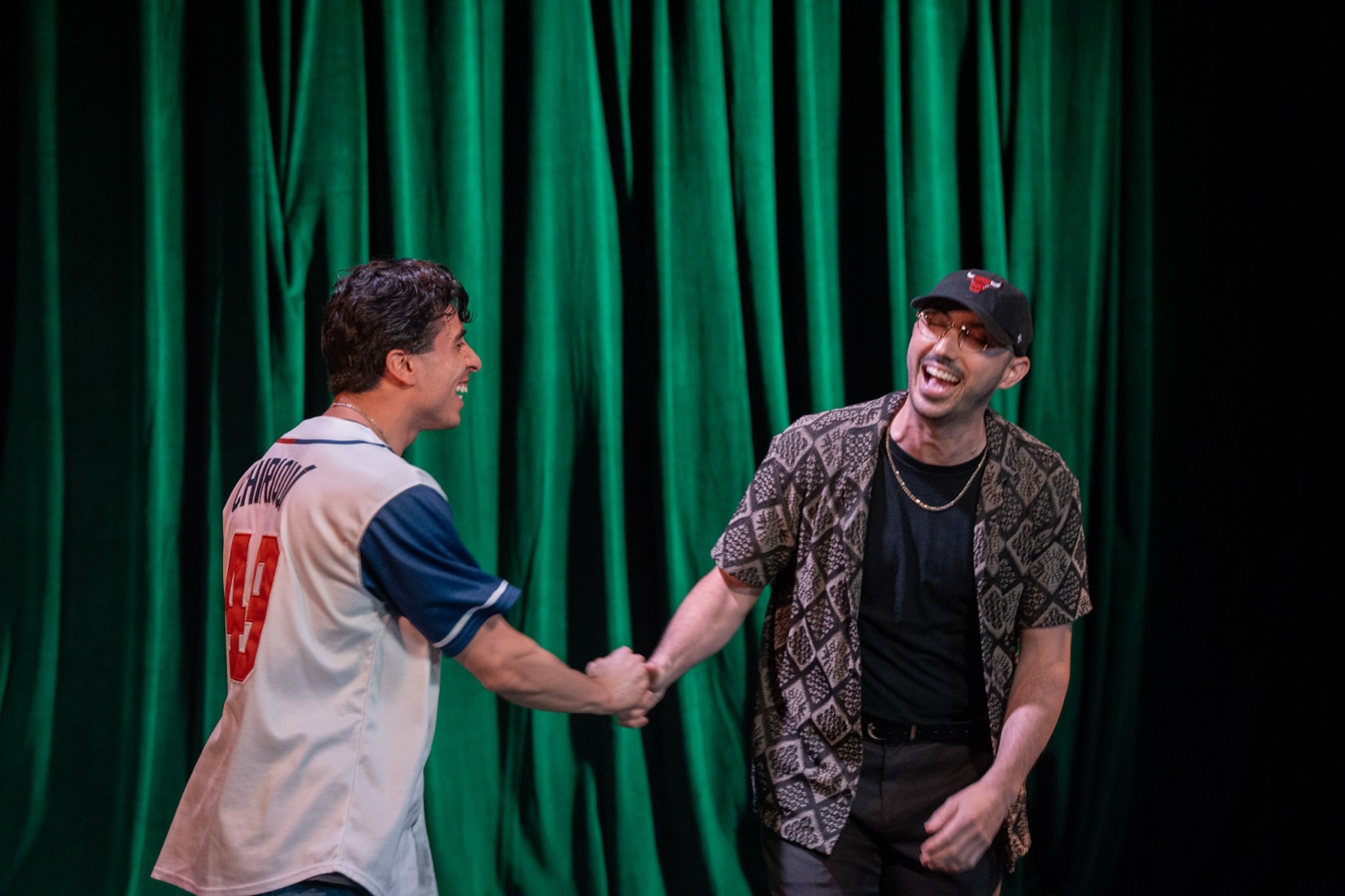 Two performers laughing and shaking hands on stage
